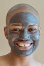 Smiling black woman with clay facial mask looking at camera