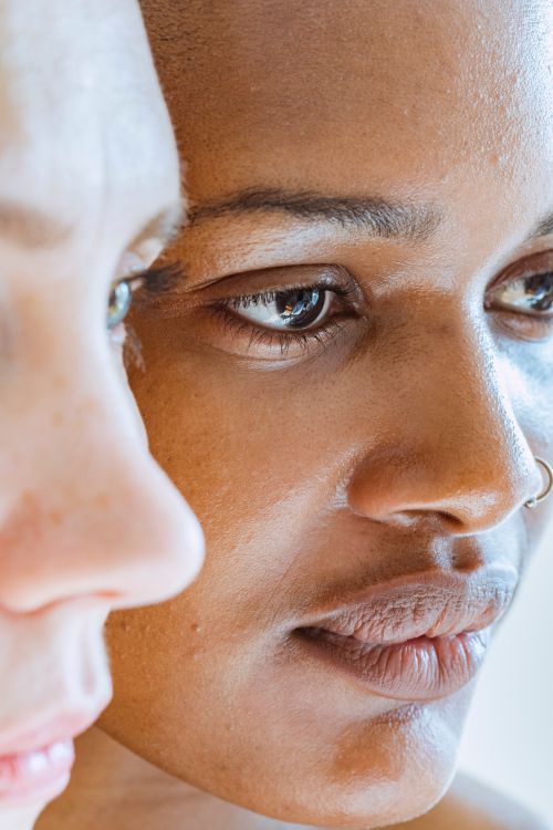 Free Closeup of crop diverse women standing close to each other and looking away against blurred light background Stock Photo