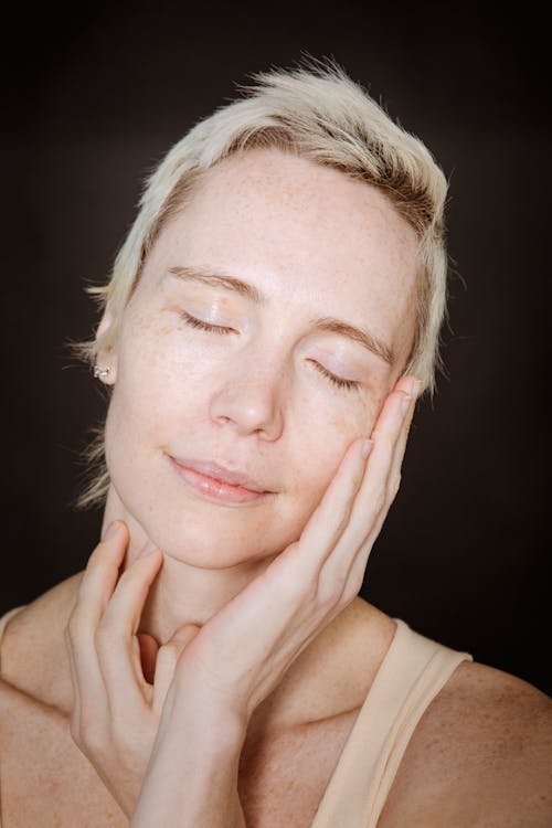 Free Young woman with closed eyes touching face Stock Photo