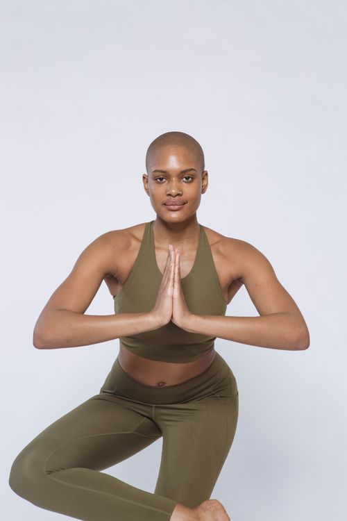 Free Sporty African American female with short hair in sportswear doing Ardha Padmasana posture while looking at camera on white background during yoga training Stock Photo