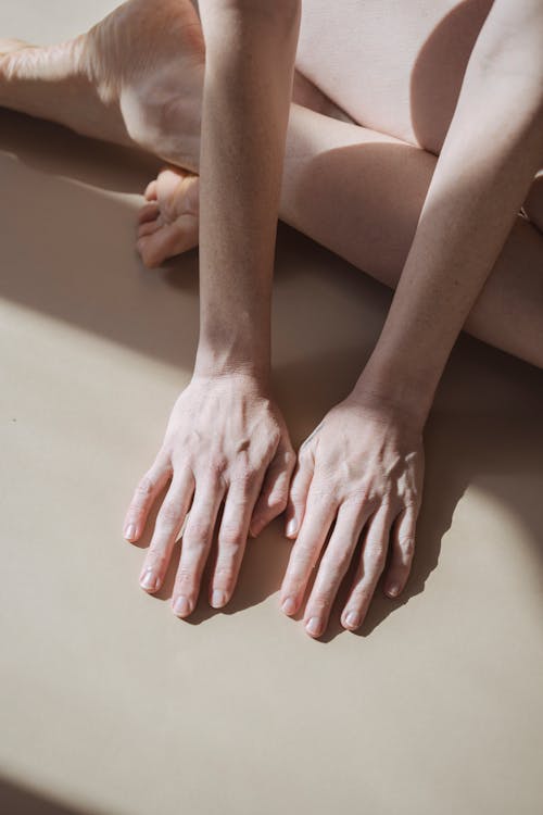 Free Crop barefoot person touching white floor in sunlight Stock Photo