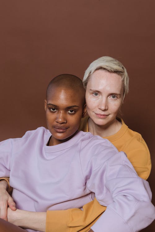 Free Blond lady hugging black female partner in studio Stock Photo