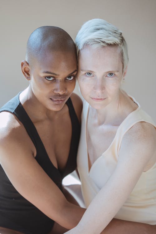 Diverse women hugging against gray wall