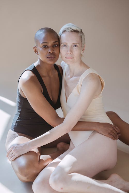 Calm multiracial women hugging against white background