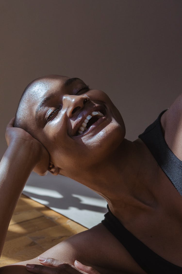 Smiling Black Hairless Woman Lying On Floor