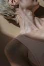 Crop unrecognizable female in beige top lying on floor in bright beam of sunshine