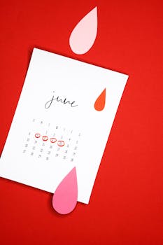 A minimalist June calendar design with abstract shapes on a vibrant red background.