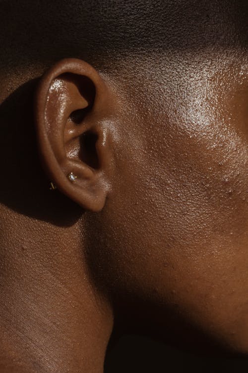 Side view of crop face of anonymous African American lady with piercing in ear