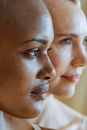 Side view of hairless African American female and blurred blond woman looking away