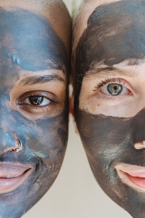 Free Crop cheerful multiethnic ladies with clay mask applied on faces looking at camera Stock Photo
