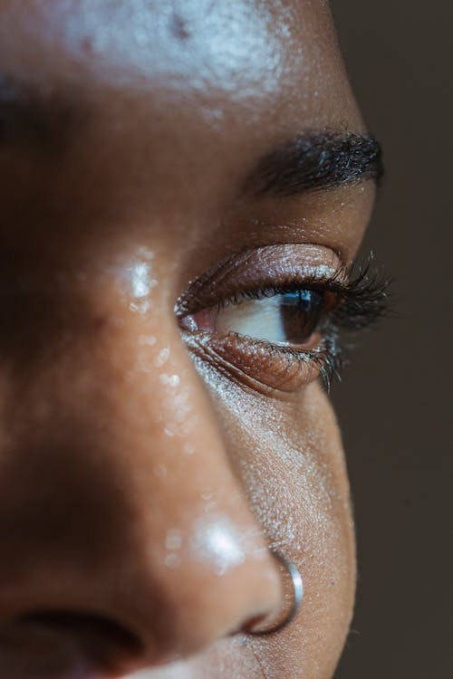 Closeup of crop black lady with shiny face skin and nose piercing looking away