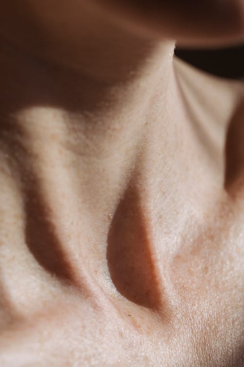 Bare neck with suprasternal notch of crop anonymous person with brown skin in sunlight