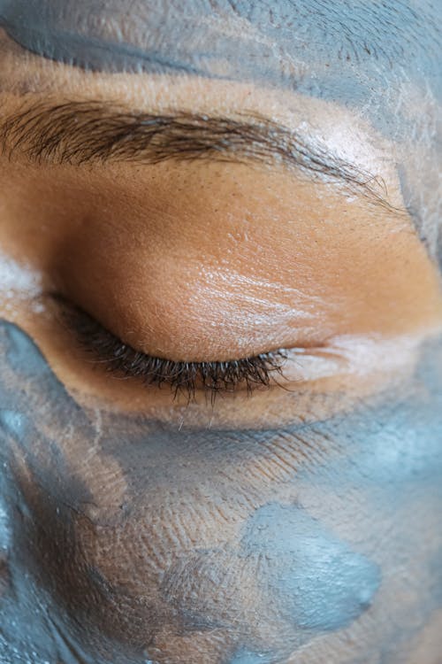 Closeup crop face of ethnic woman with closed eyes and clay mask applied on skin