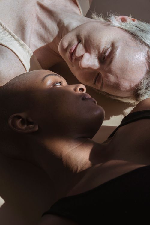 Free From above of diverse women looking at each other while lying in shadow Stock Photo