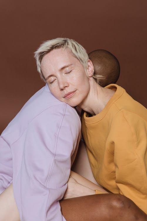 Free Calm young diverse woman models in casual clothes putting heads on shoulders of each other with closed eyes Stock Photo