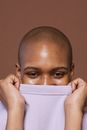 Positive black woman covering half face with t shirt