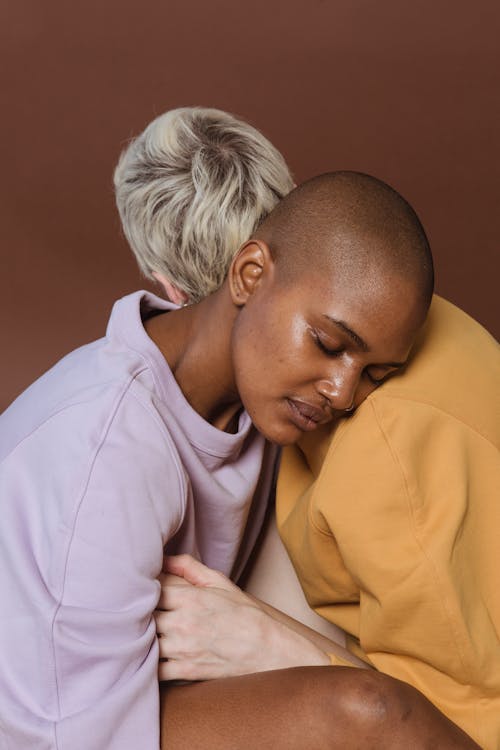 Free Young African American female model in casual outfit embracing blonde person putting head on shoulder with closed eyes Stock Photo