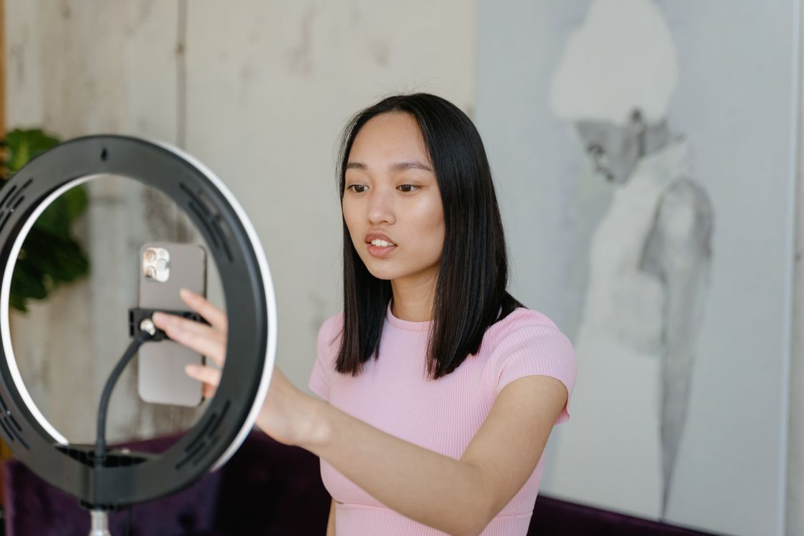 Short-form video creator recording with a phone and ring light for TikTok advertising