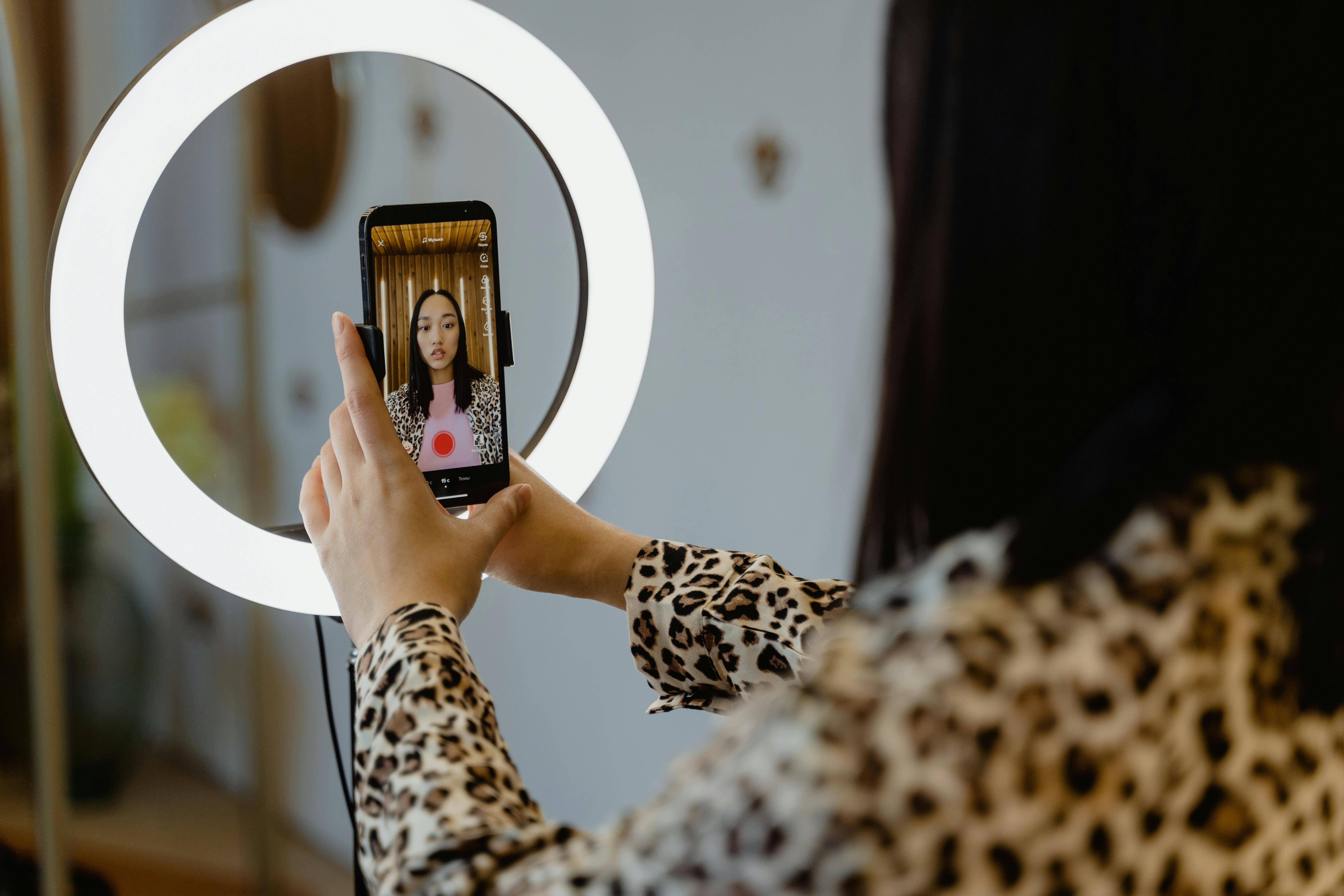 A person recording themselves with a smartphone in front of a ringlight