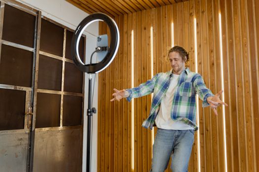 A man enjoys dancing in a modern wooden room with a ring light setup.