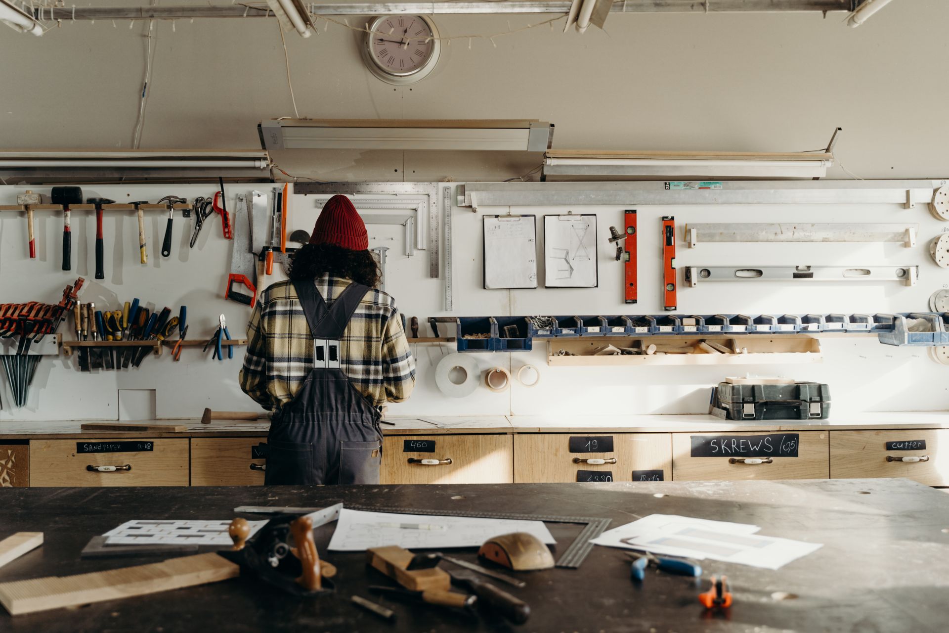 A carpenter shaping wood at a bench in a rustic workshop