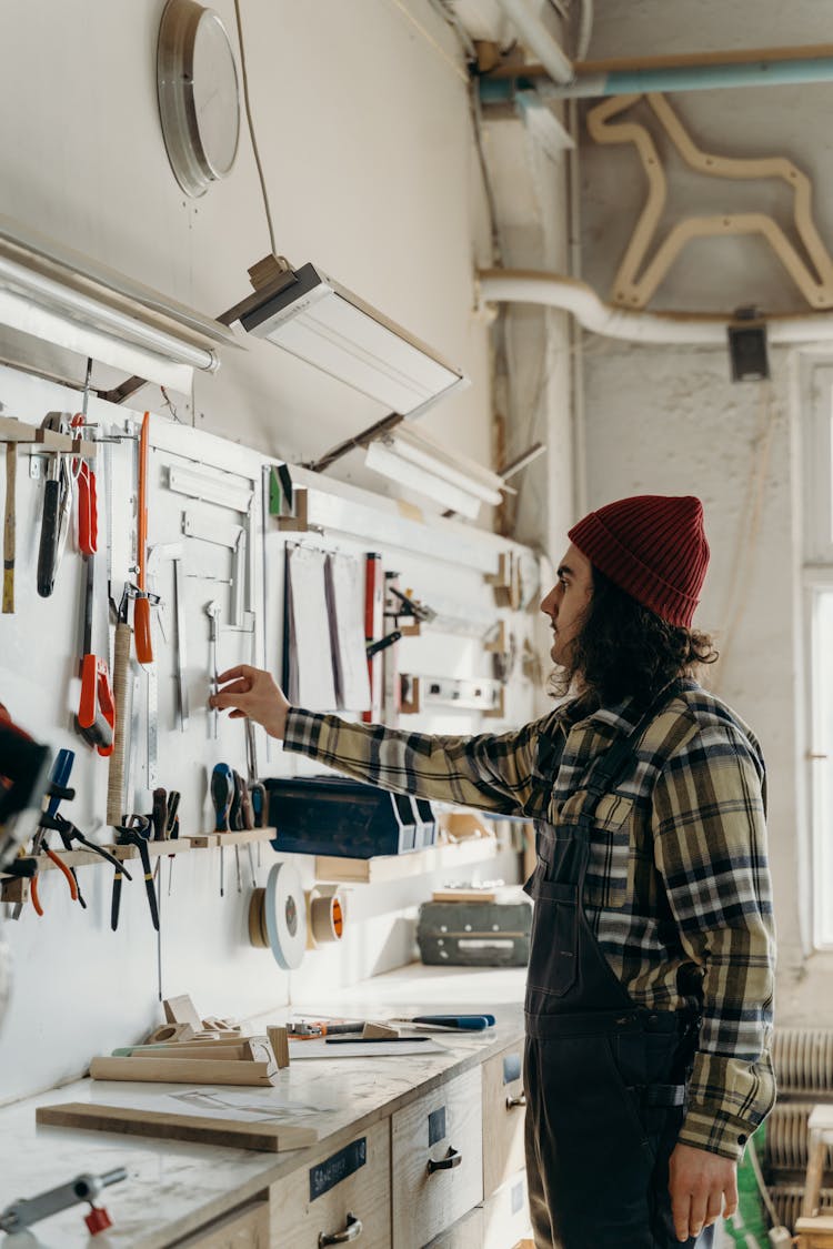 Man In Plaid Long Sleeves And Jumper Getting A Tool On A Wall 