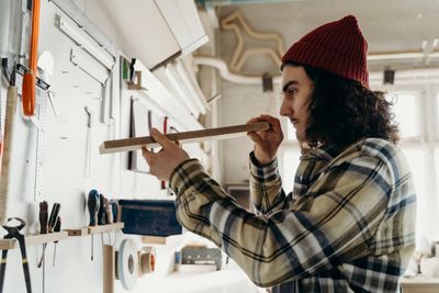 Skilled carpenter measuring a wood plank with precision in a naturally lit workshop