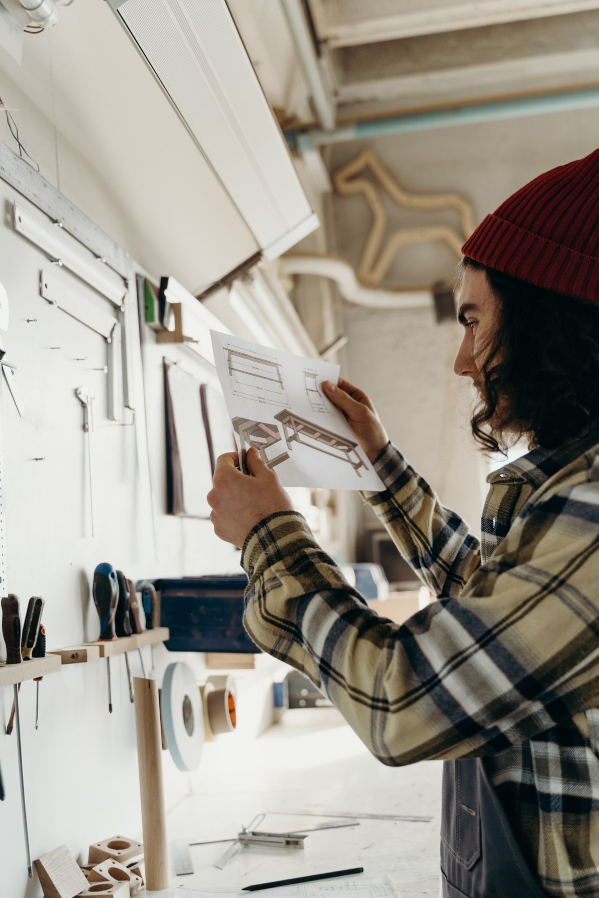 Craftsman reviewing a furniture design blueprint in the workshop