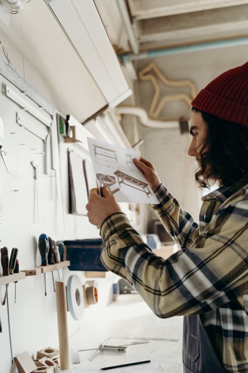 Maker checking a drawing in a woodworking workshop — photo by cottonbro studio on Pexels