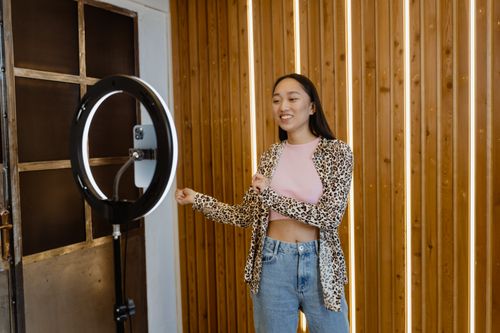 Free A young woman enjoys dancing indoors with a ring light and smartphone setup, capturing a fun moment. Stock Photo
