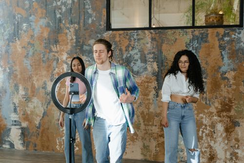 Free Friends recording a dance video for social media with a ring light and smartphone. Stock Photo