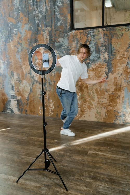 Free A man poses for a video with a ring light and smartphone setup in a trendy studio. Stock Photo