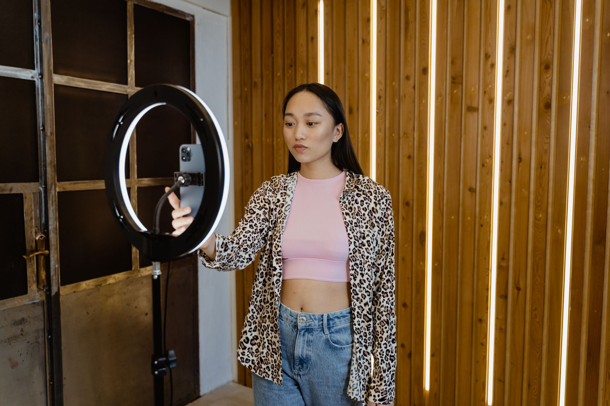 An asian woman influencer filming a vlog with a ring light in a stylish indoor setting.