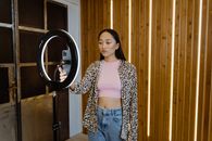 Woman in White and Black Leopard Print Long Sleeve Shirt Standing Near Brown Wooden Cabinet