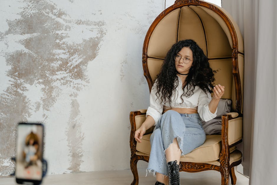 Modern woman sitting in ornate chair with smartphone in stylish loft interior.