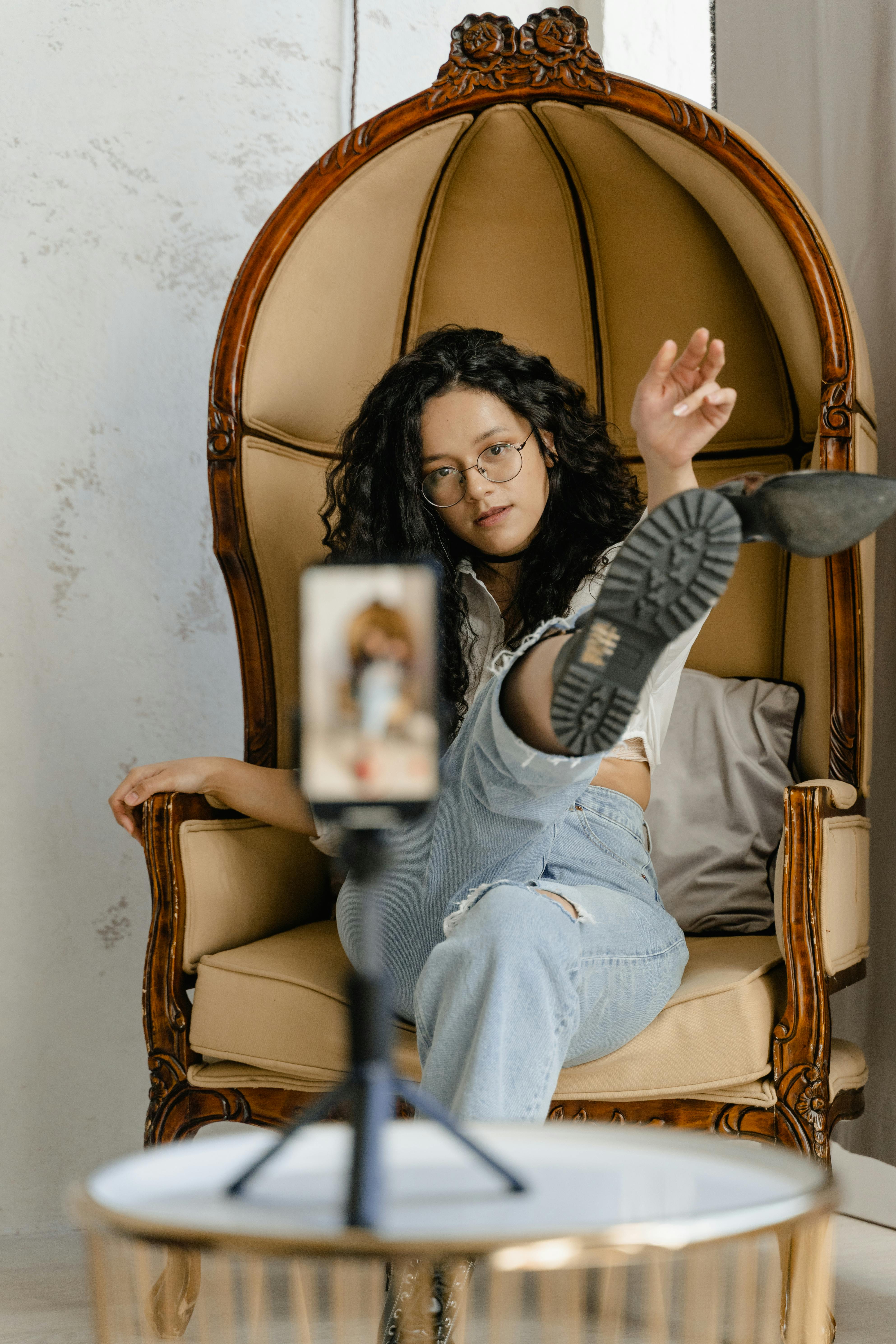 a woman taking a picture of a herself sitting on a chair