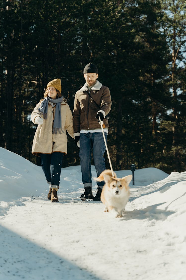 Man Holding The Leash Of A Dog Beside A Woman