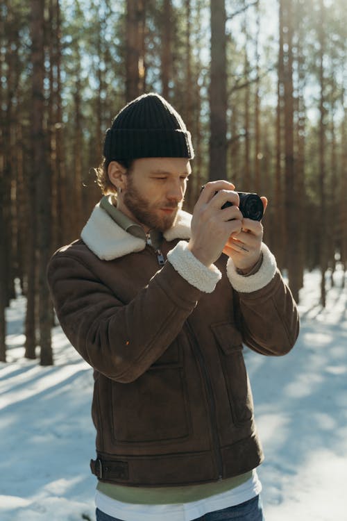 Free Man in Black Knit Cap and Brown Coat Holding Black Dslr Camera Stock Photo