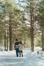 Man in Gray Jacket and Blue Denim Jeans Walking on Snow Covered Ground Surrounded by Trees