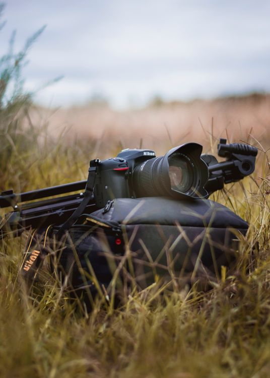 Camera In Field Black Camera on Brown Grass Field · Free Stock Photo
