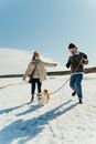 Man and Woman Holding Hands While Walking on Snow Covered Ground