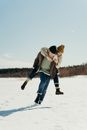 Man in Brown Jacket and Blue Denim Jeans Walking on Snow Covered Ground