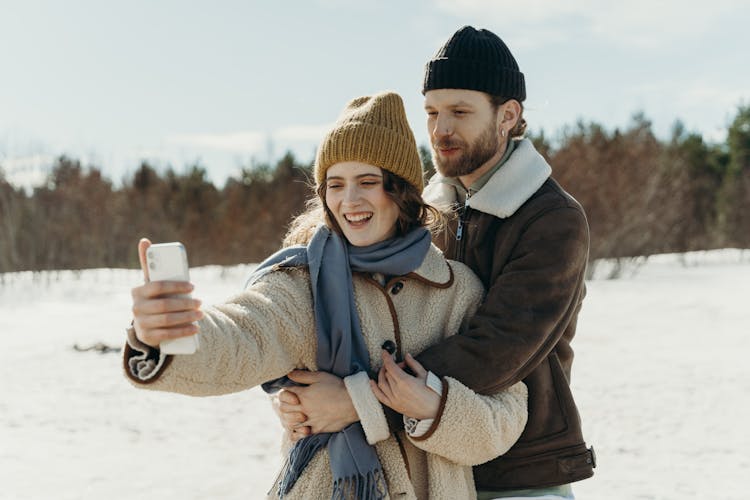 A Couple In Winter Clothing Taking A Selfie