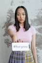 Woman in Pink and White Stripe Shirt Holding White Card