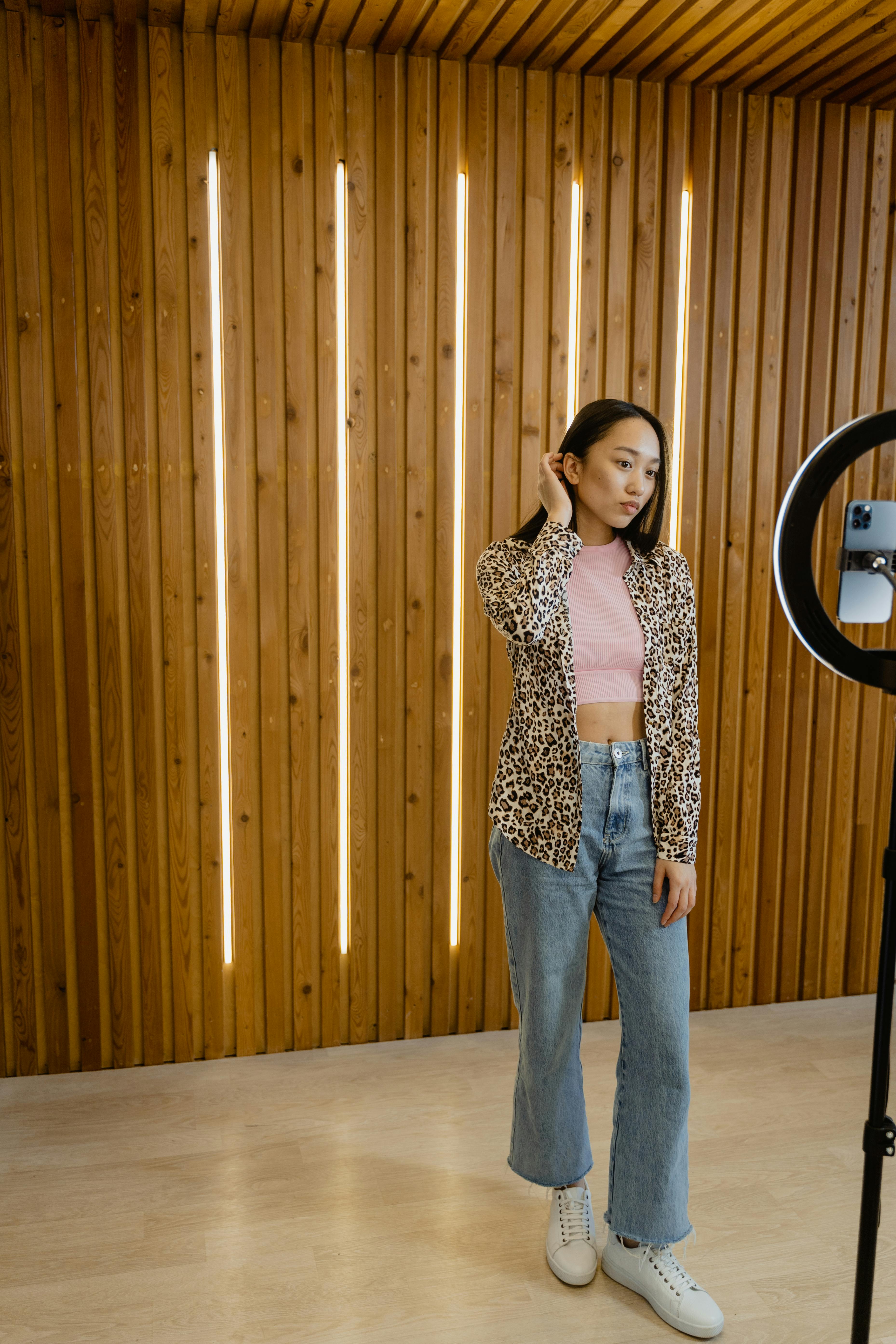 woman in brown and black leopard print long sleeve shirt and blue denim jeans standing beside