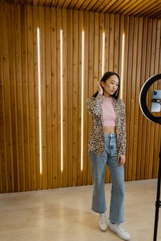 A fashionable young woman poses in a contemporary room, highlighting trendy style and wooden decor.