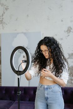 Young woman adjusting a ring light indoors, perfect for vlogging and content creation.