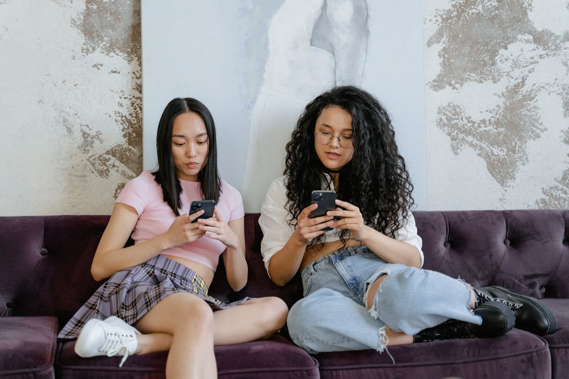 Two Girls Using Smartphones Sitting on a Couch