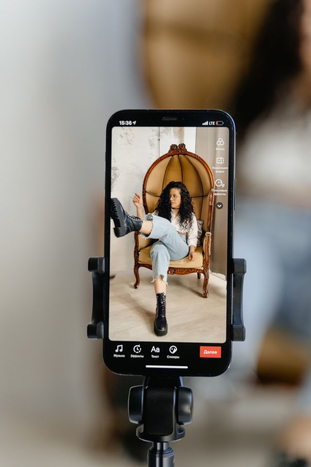 Un móvil en un trípode muestra en su pantalla a una mujer sentada en una silla de mimbre