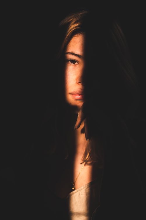 Free Captivating portrait of a woman with dramatic light and shadow effect. Stock Photo